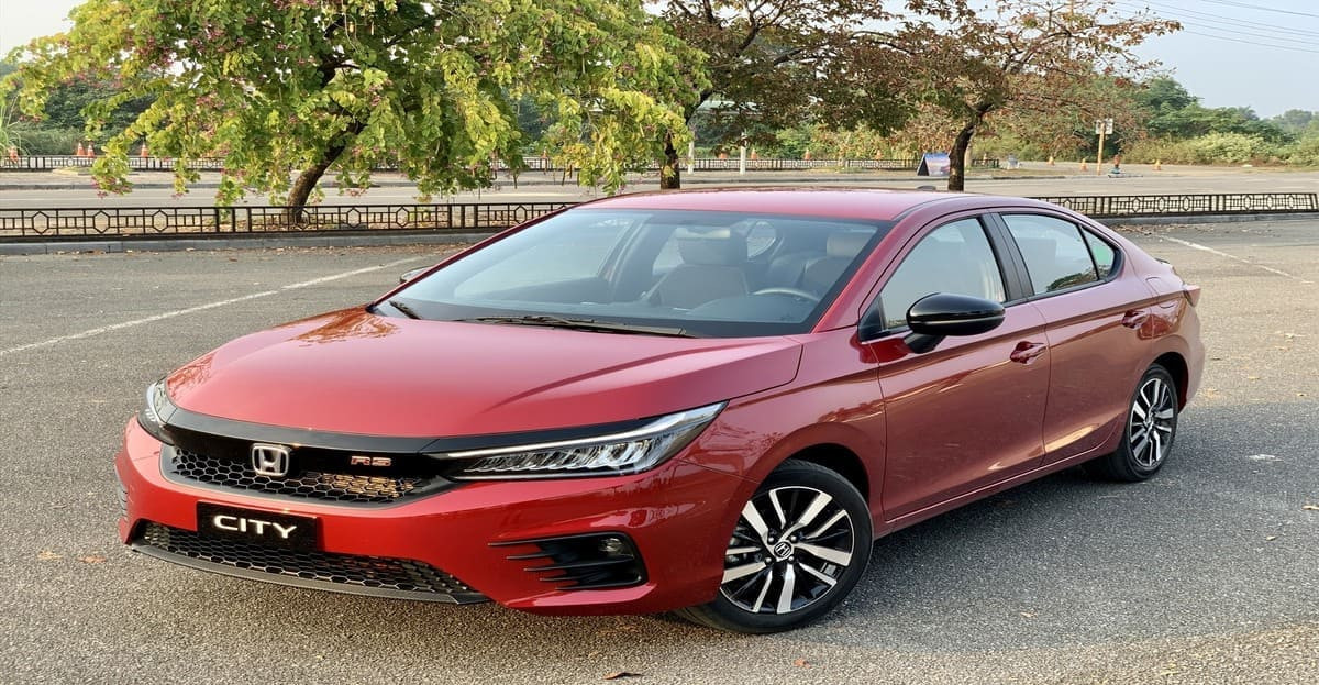 Alt text: Hình ảnh một chiếc xe Sedan hạng B màu đỏ đang di chuyển trên đường phố.